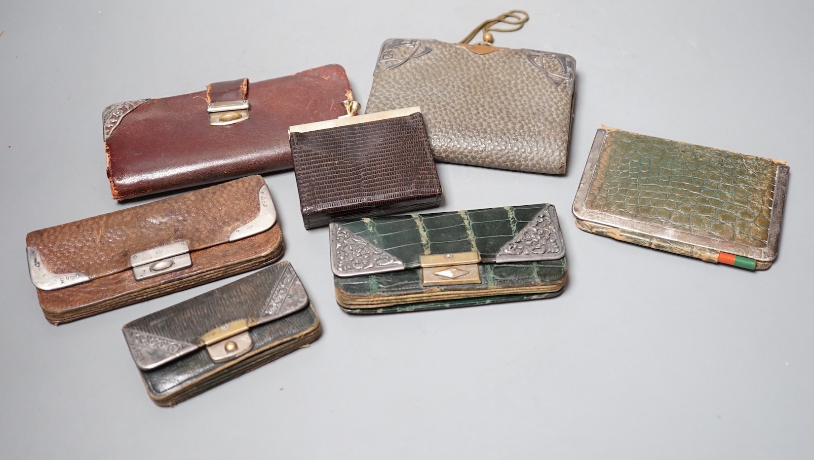 Five assorted early 20th century silver mounted leather purses including Art Nouveau, a similar notebook and one other purse.